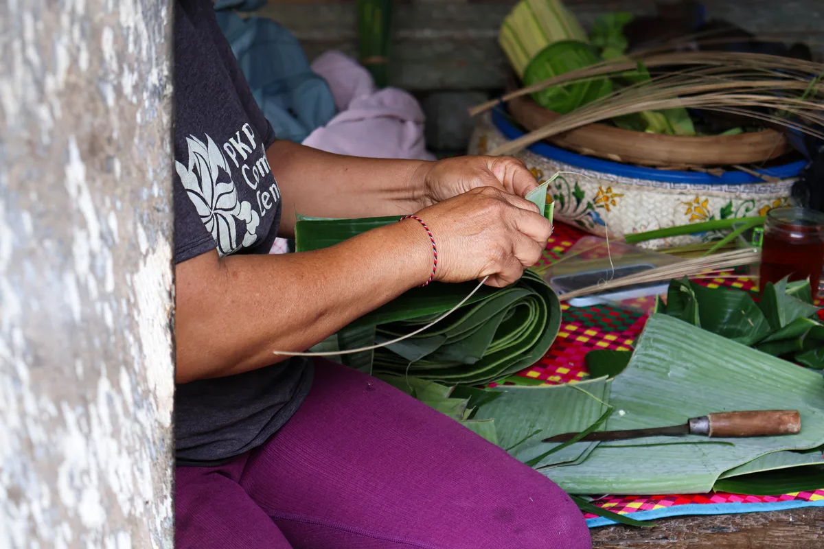 A woman weaving palm leaves, a traditional Balinese craft, at PKP